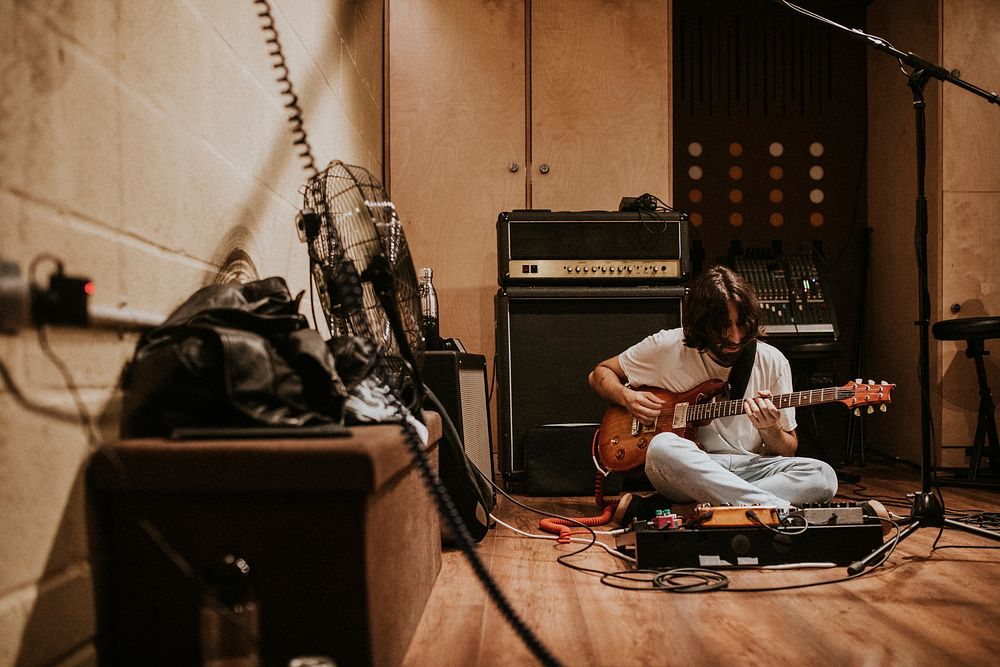 Guitarist recording rock music in studio, sitting on the floor
