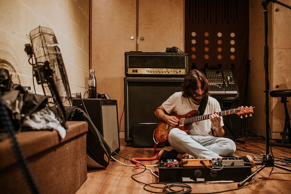 Guitarist playing music, studio recoding, sitting on the floor