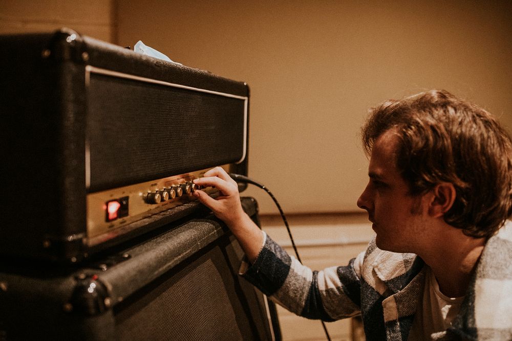 Musician setting guitar amp, studio recording session photo 