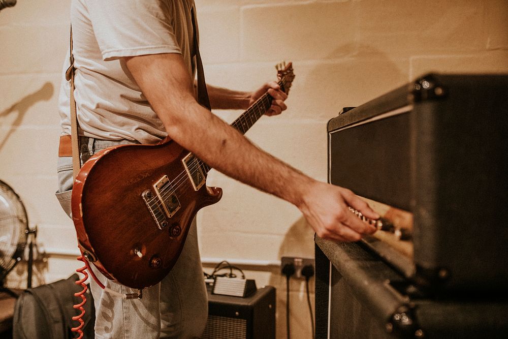 Musician setting guitar amp, studio recording session photo 