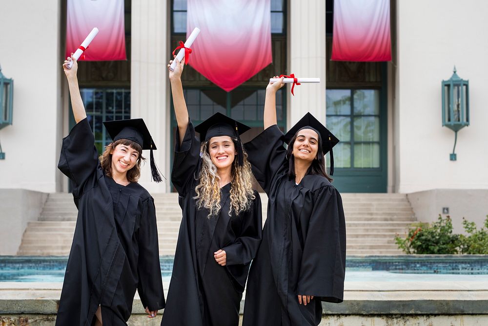 Happy female students graduating university, celebrating with diplomas