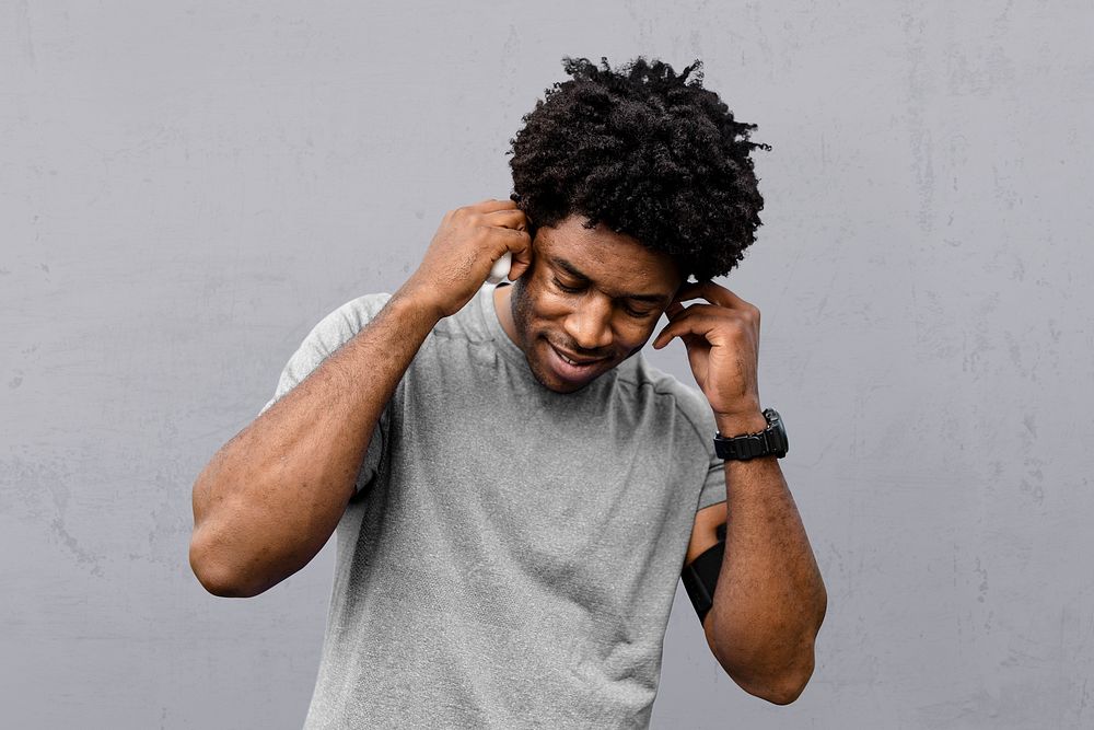 Man athlete putting the earbud on his ears and listening to the music