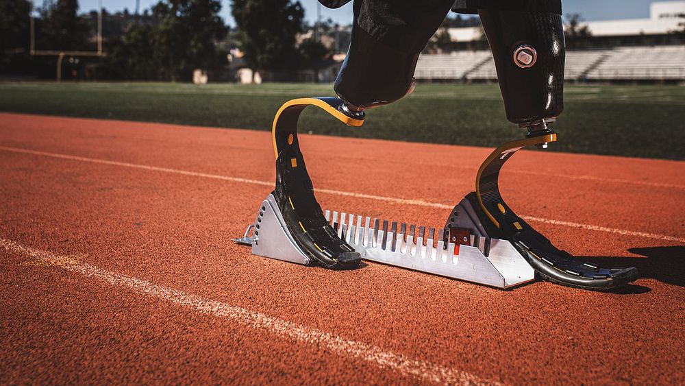 Athlete with prosthetic legs on sprint starting block 