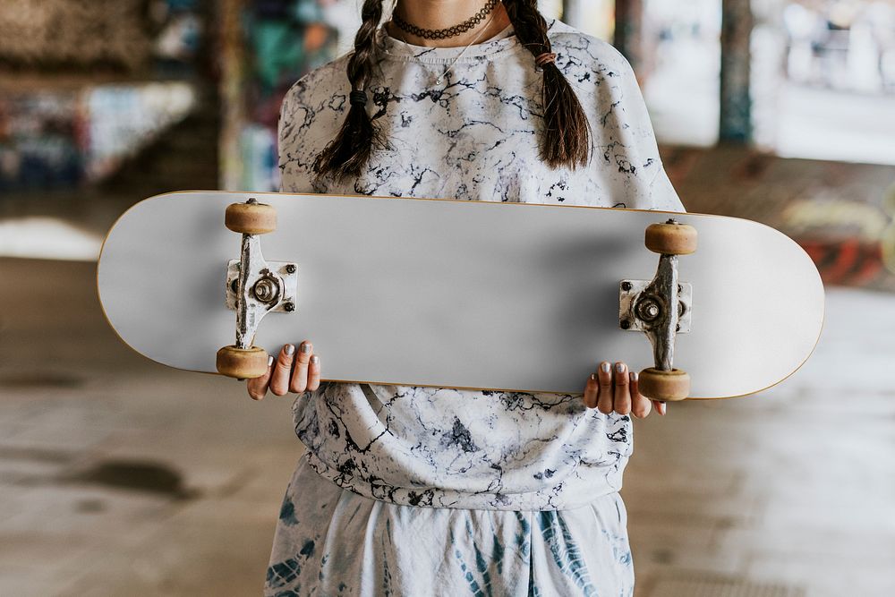 Cool woman holding white skate board in skate park