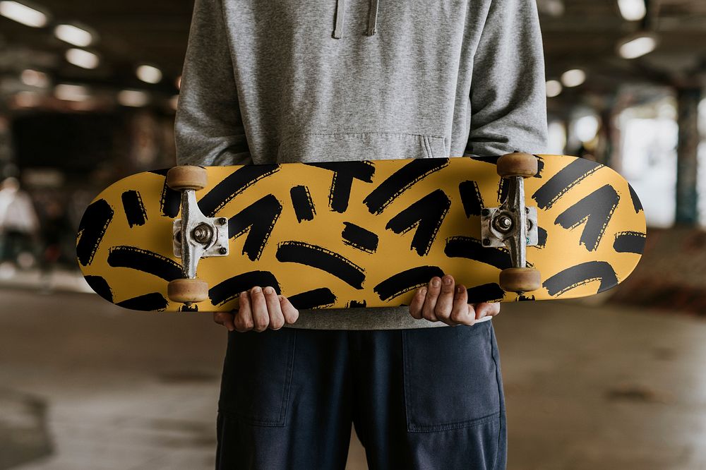 Skate holding patterned yellow skateboard