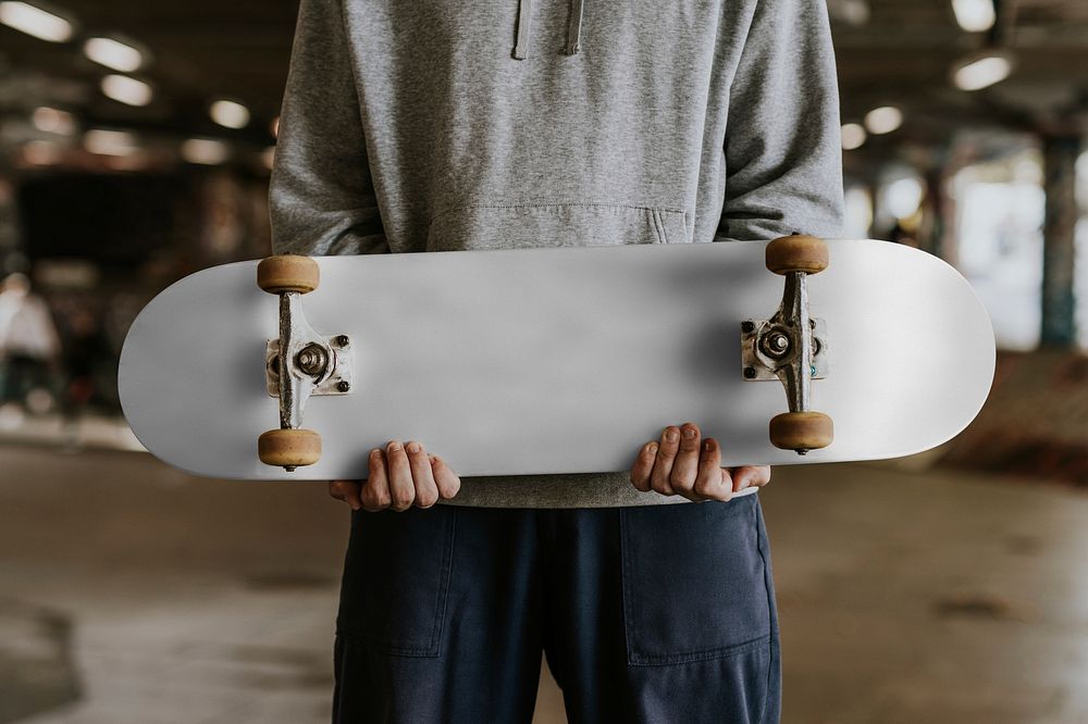 Man holding white skateboard in skate park