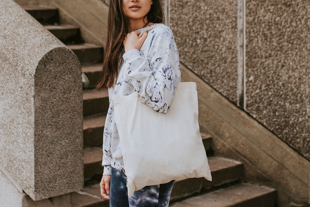 Woman with white tote bag, standing by staircase