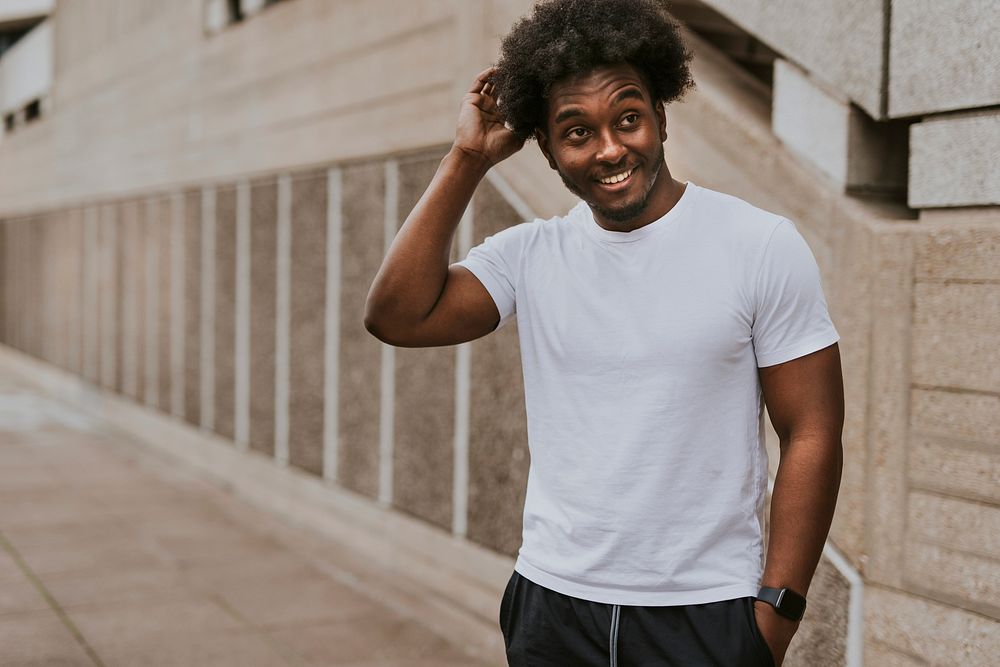 Smiling man in simple white tee, standing by staircase