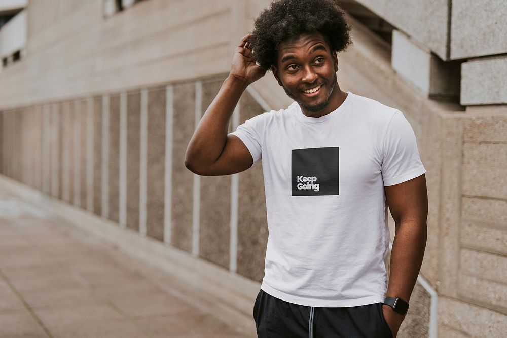 Happy black man in white tee standing by staircase