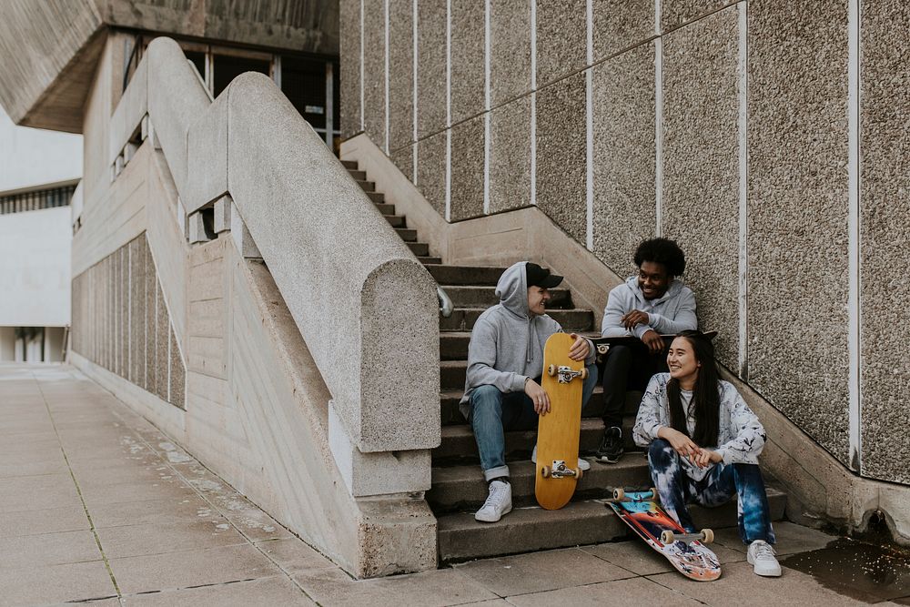 Diverse friends talking at stairs with skateboards