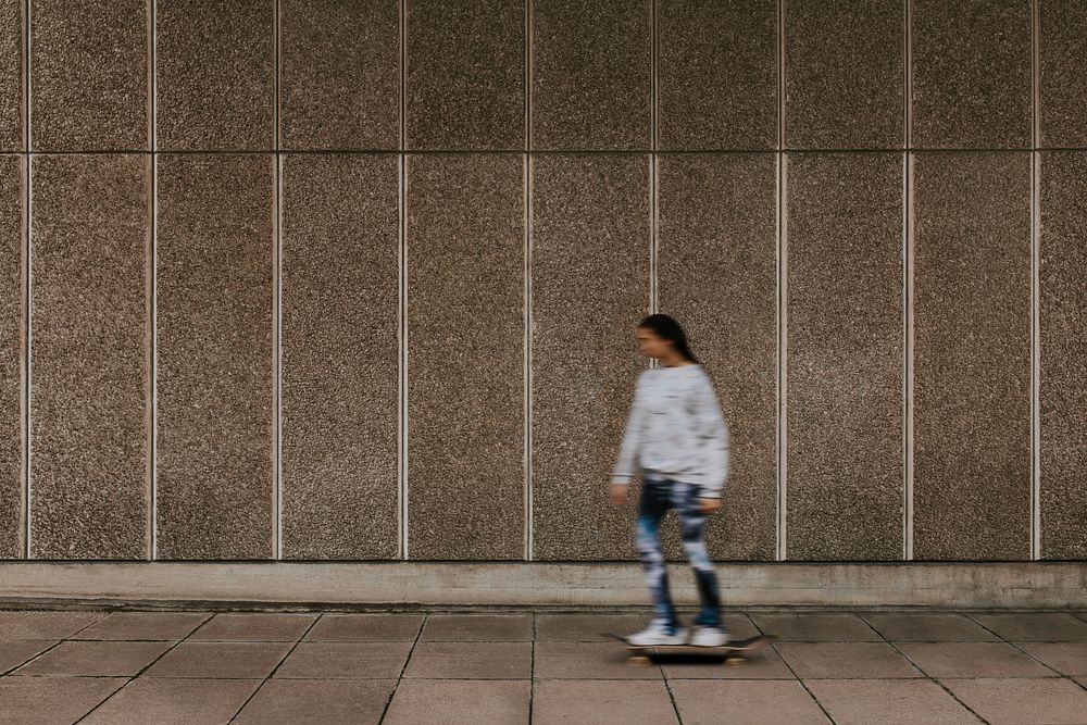 Woman skating in city, passing grunge wall