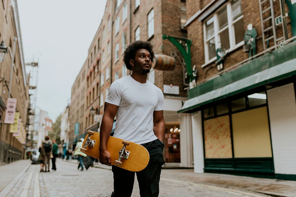 Man walking in town with wooden skateboard