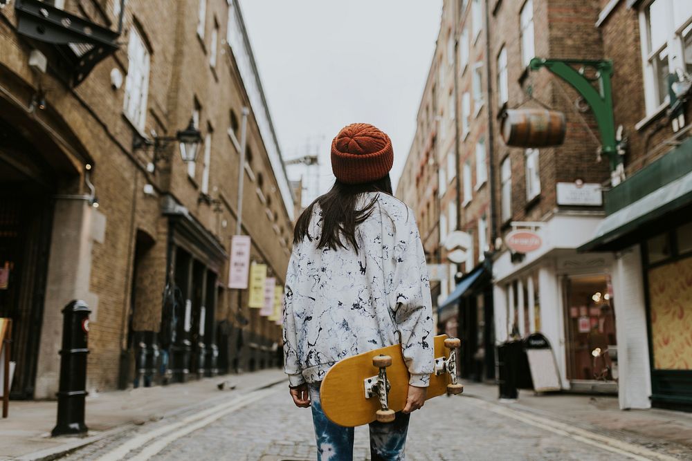 Woman walking with yellow skateboard in town