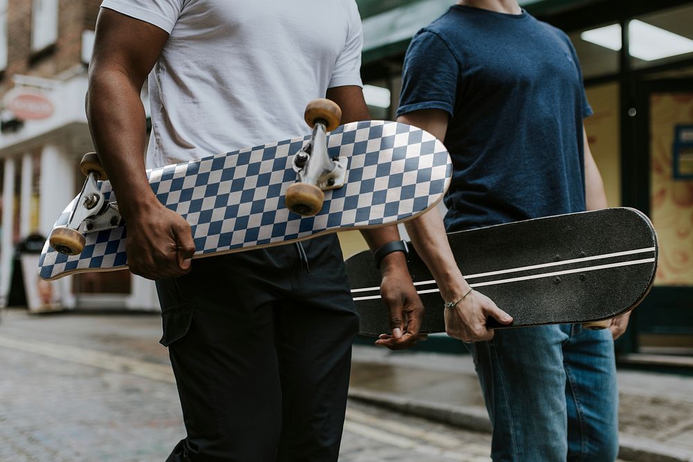 Diverse men walking with skateboards in hands
