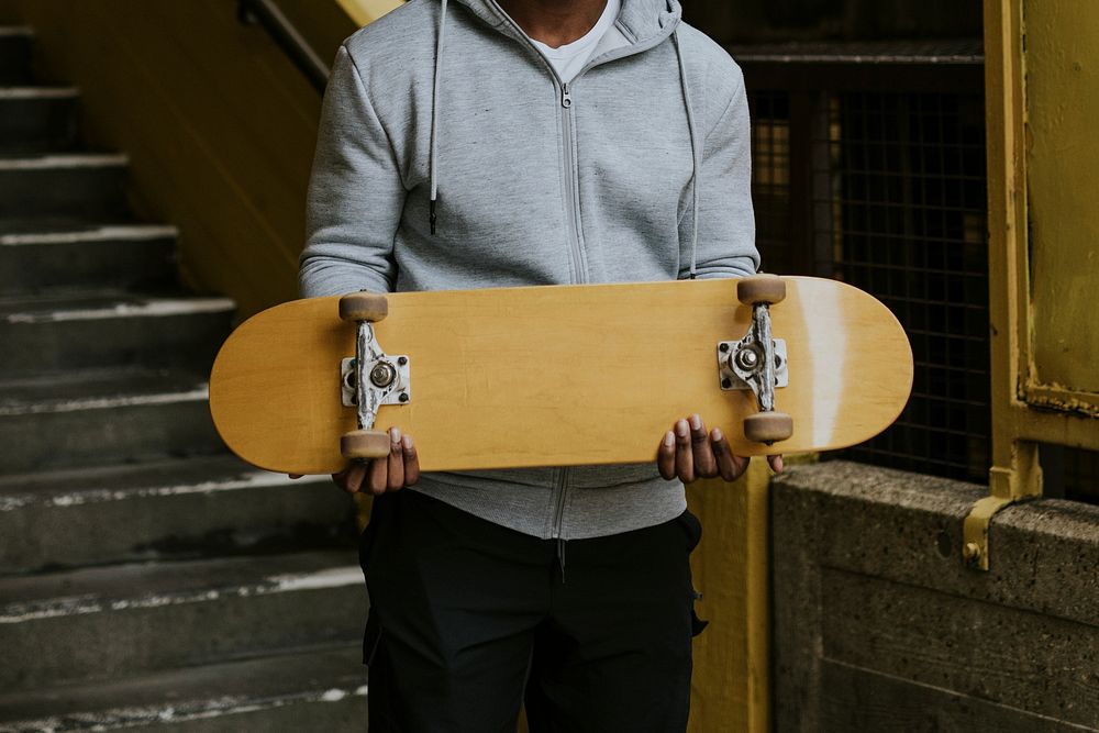 Man holding yellow skateboard, extreme sport game