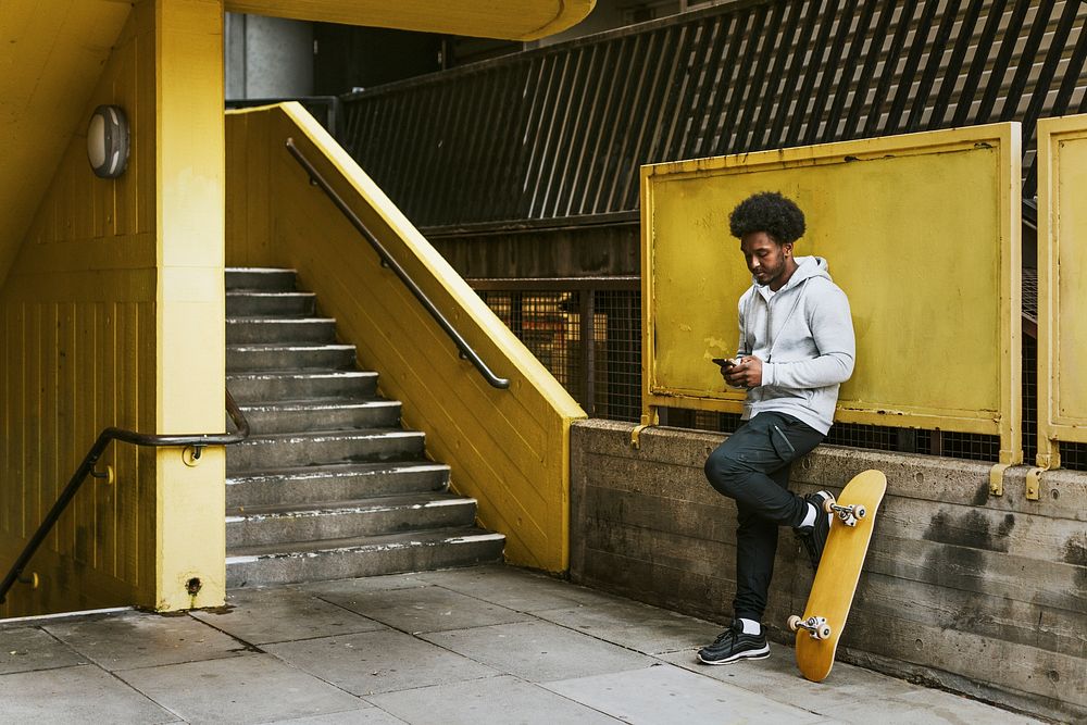 Male skater texting at yellow stairs