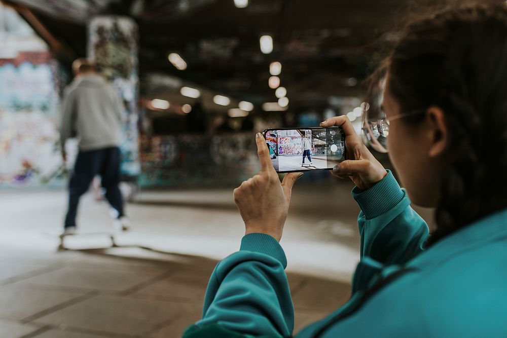 Woman capturing skater by phone