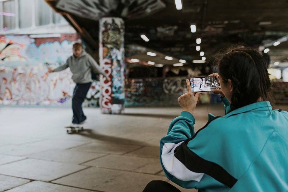 Woman capturing man skating at skate park