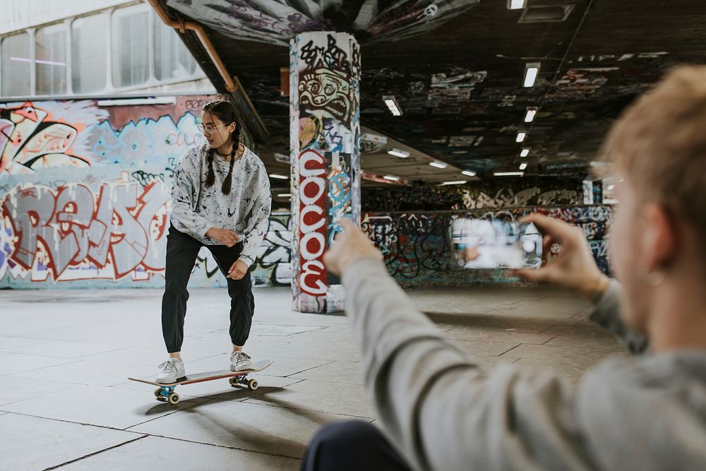 Man recording female skater at skate park