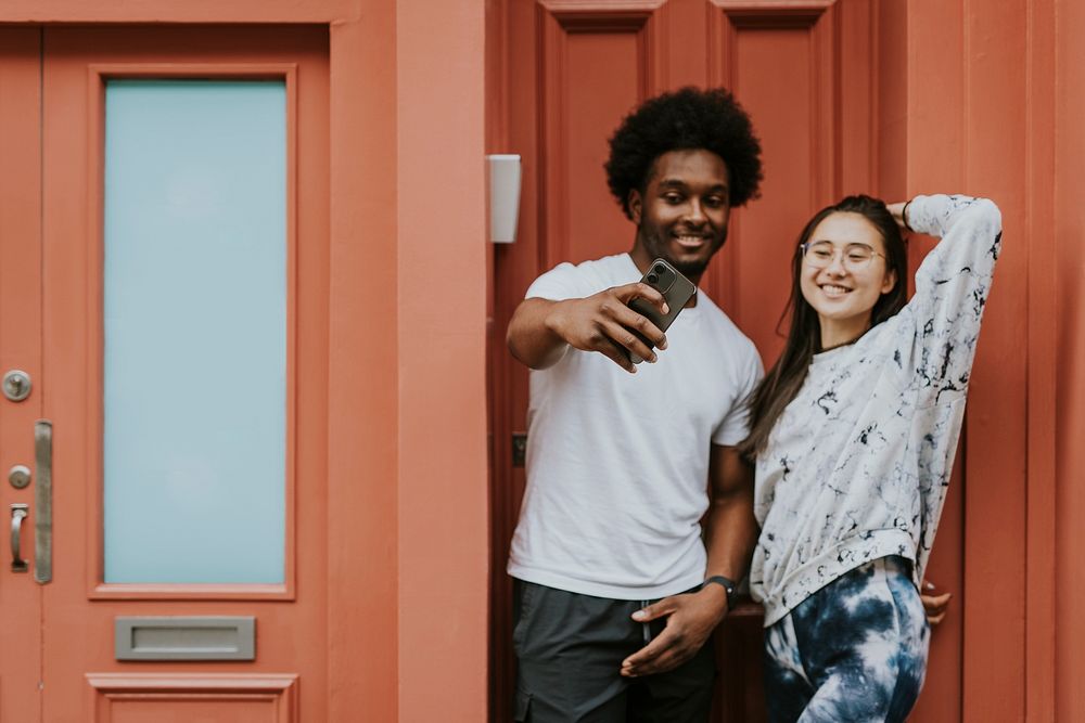 Cute couple taking selfie in front of orange store