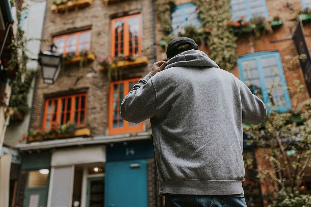 Man in gray hoodie rear view, standing in front of apartment