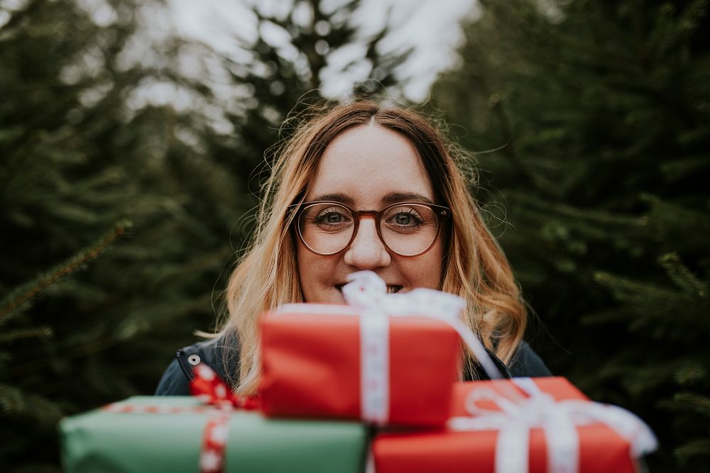 Smiling woman carrying many boxes of Christmas presents