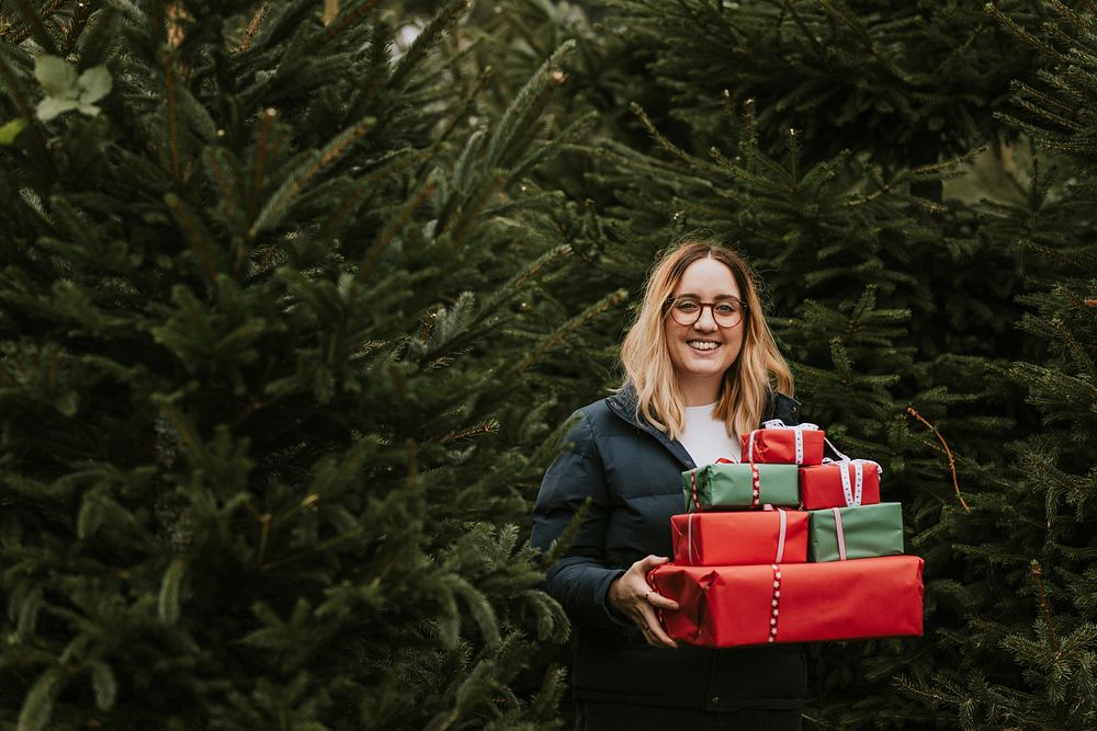 Smiling woman carrying many boxes of Christmas gifts