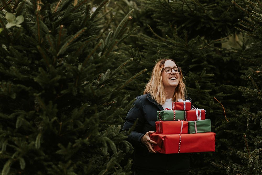 Smiling woman carrying many boxes of Christmas presents