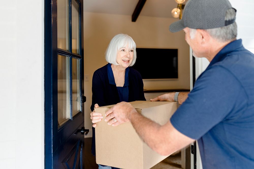 Senior woman receiving package box from delivery man, online shopping image