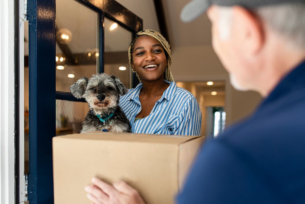 Black woman receiving package delivery, holding a dog image
