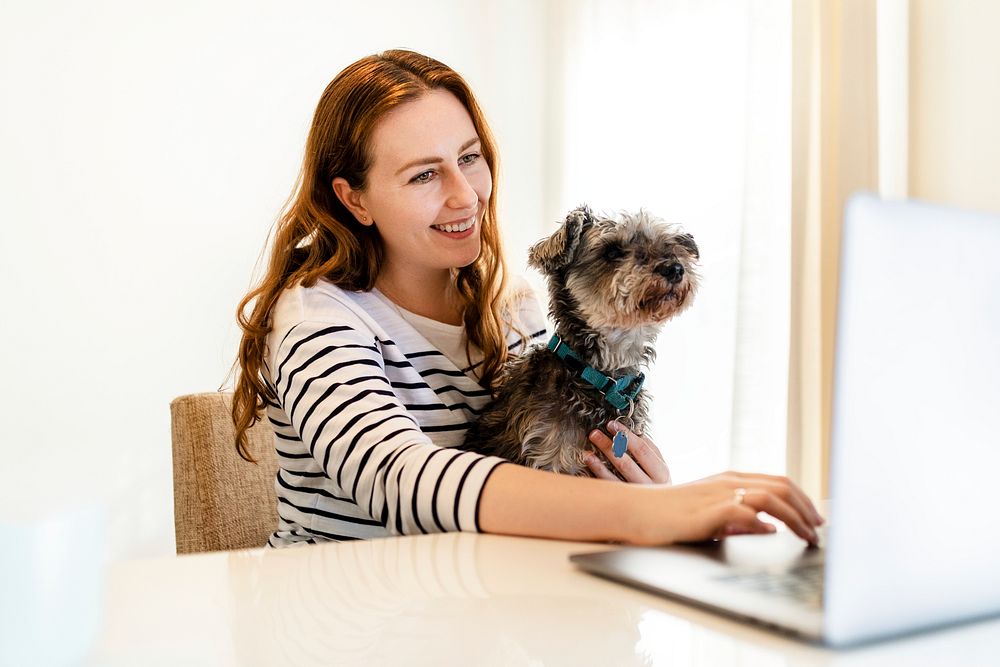 Woman working from home, dog sitting on her lap
