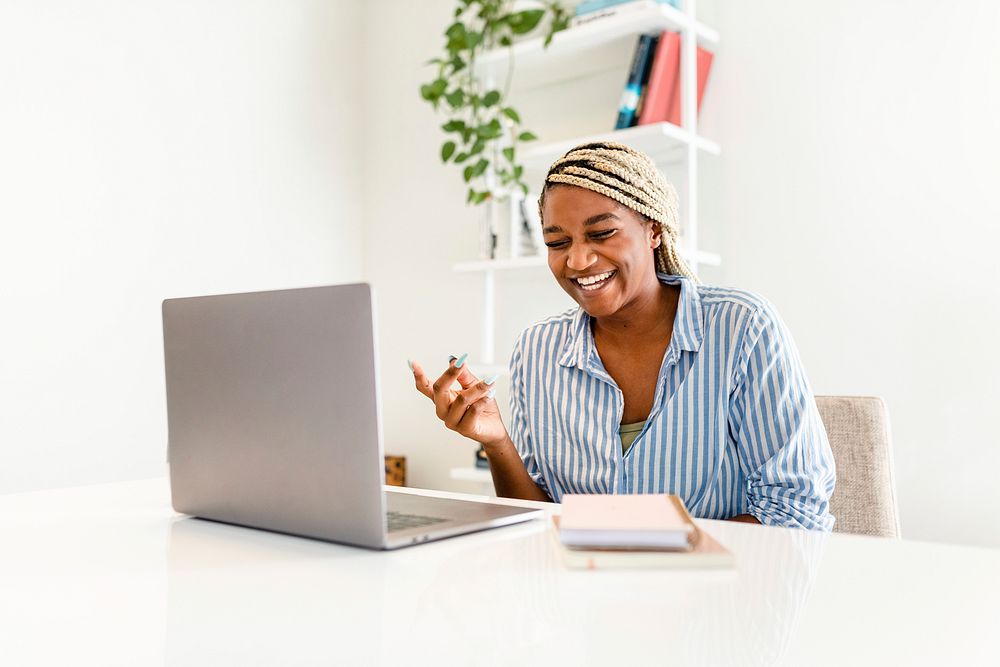 Black woman laughing during online meeting on laptop