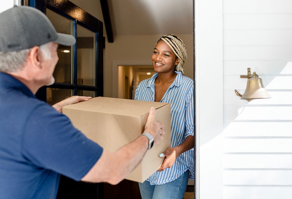 Black woman receiving package box from delivery man, online shopping image