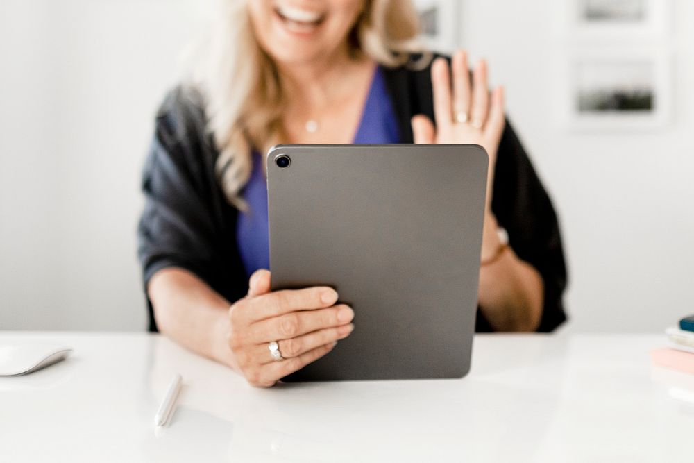 Woman waving during video call on tablet, business online meeting image