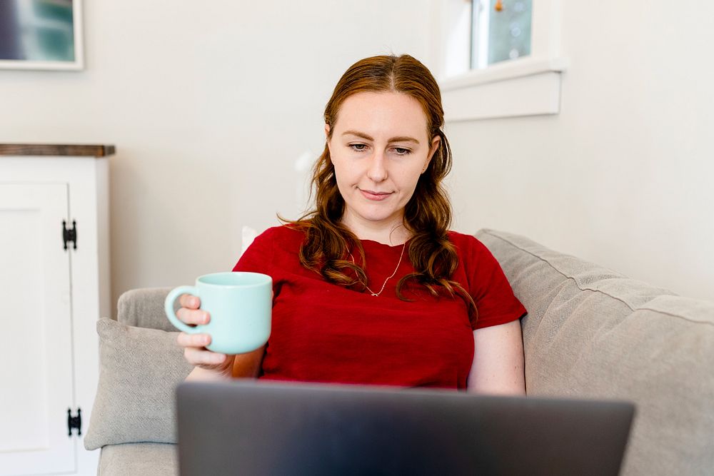 Woman working from home, holding coffee mug during the new normal