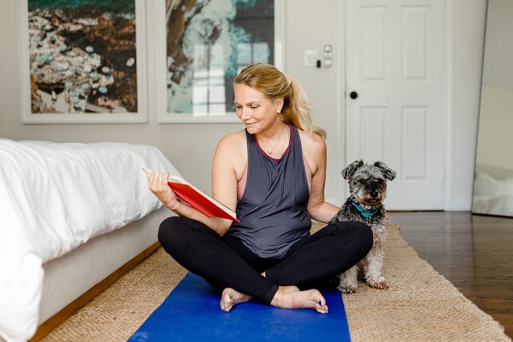 Healthy woman reading book, pet dog company at home