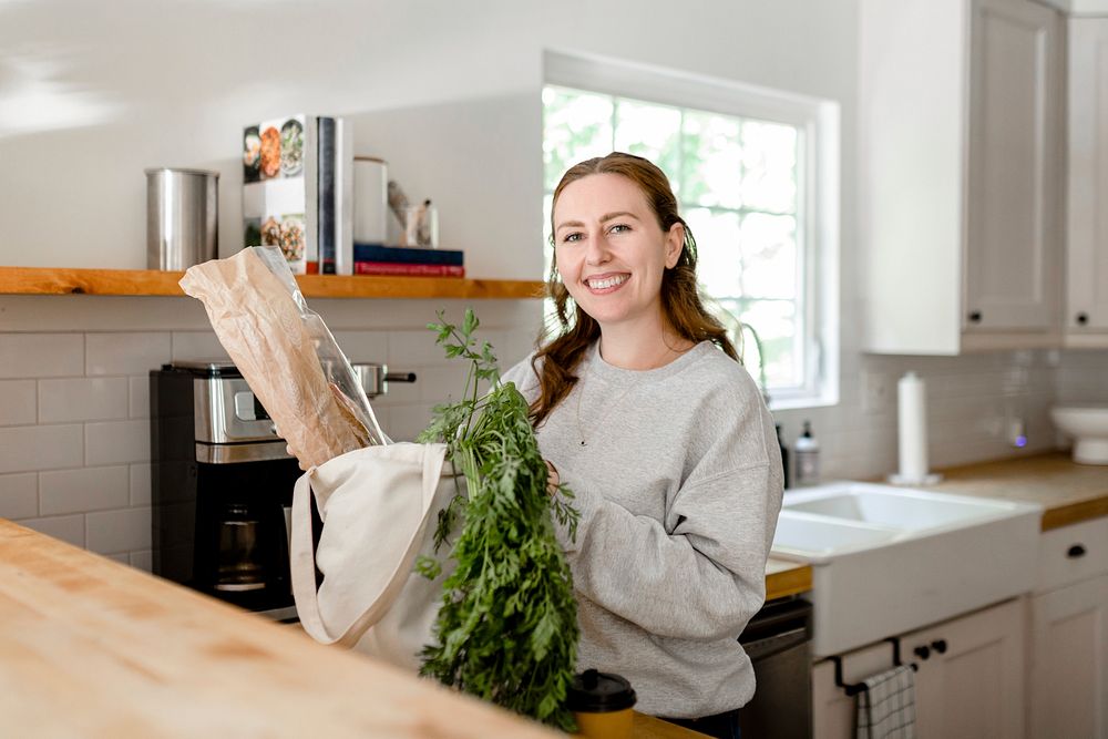 Brunette woman unpacking grocery bag in the kitchen