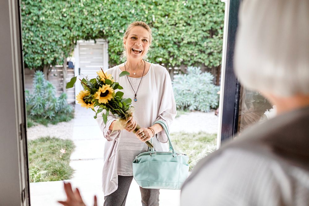 Mature woman holding sunflower bouquet, visiting neighbour