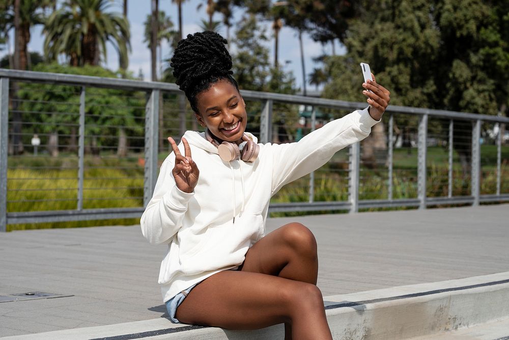 Woman in white hoodie taking selfie, streetwear fashion