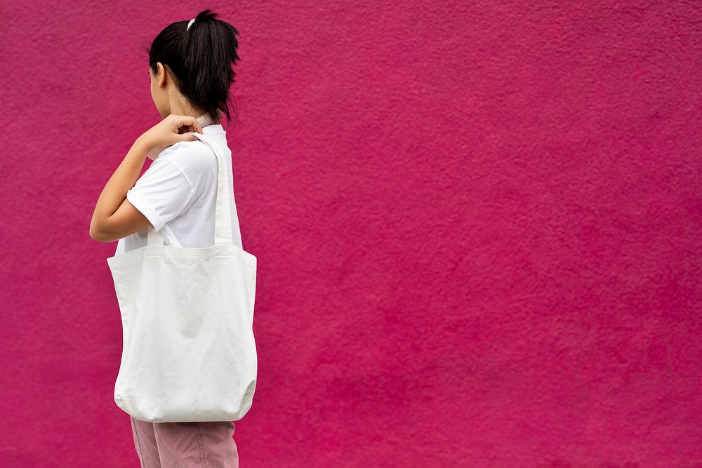 Woman with white tote bag, pink wall with design space