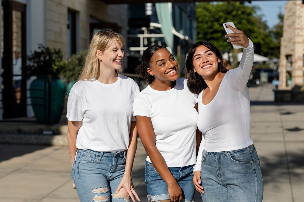 Three mixed race girlfriends taking selfie, wearing plain white apparel