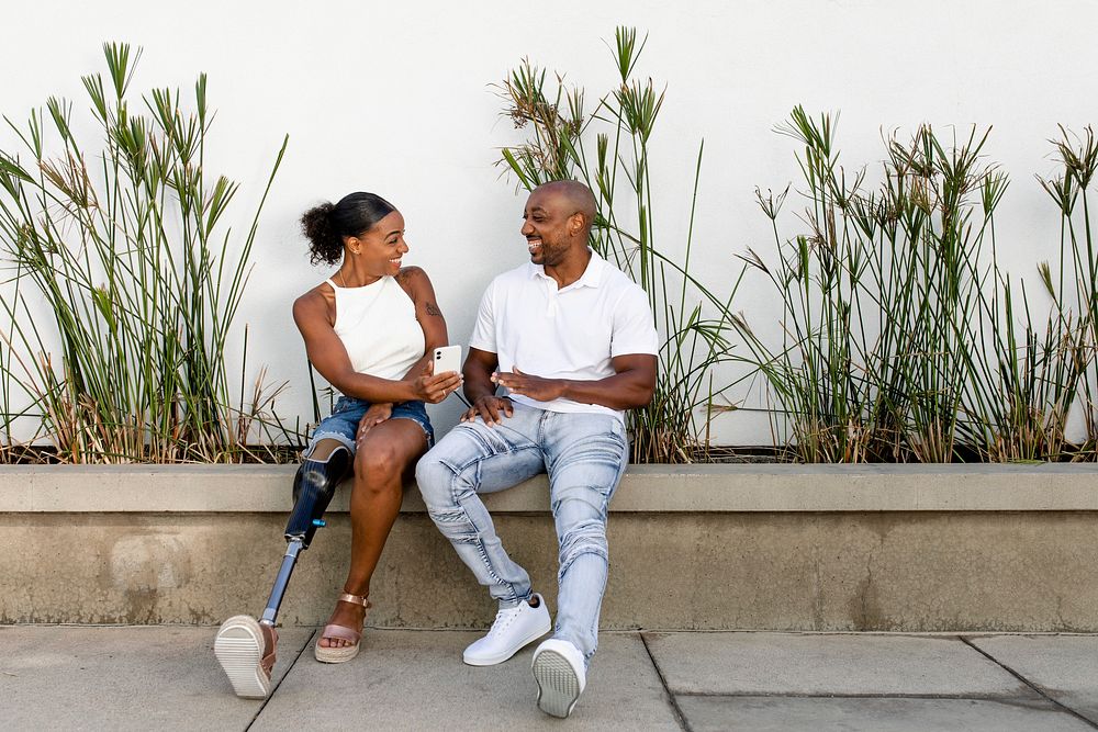 Woman showing smartphone, African American couple hanging out