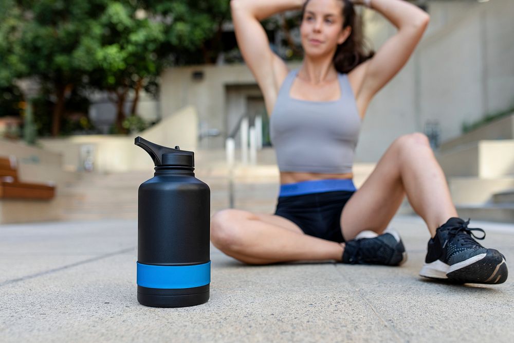 Woman sitting on the floor by reuable water bottle 