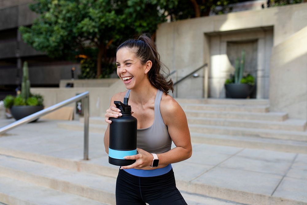 Woman drinking water from reusable water bottle during her morning exercise