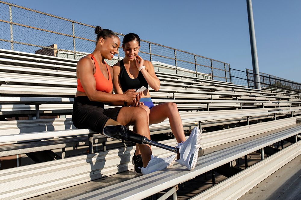 Women athletes resting and looking at a phone by the stadium