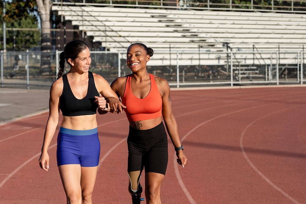 Two athletes laughing and talking to one another while on a running track
