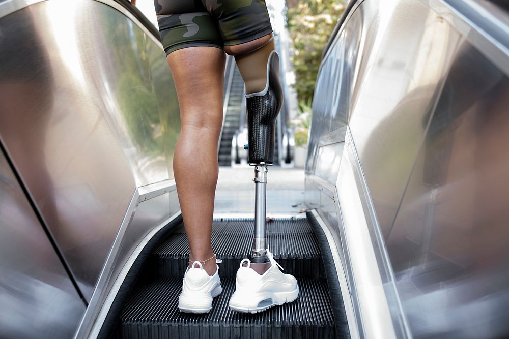 Woman with prosthetic leg using escalator