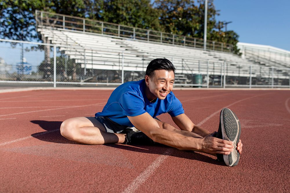 Asian man stretch by the running track 