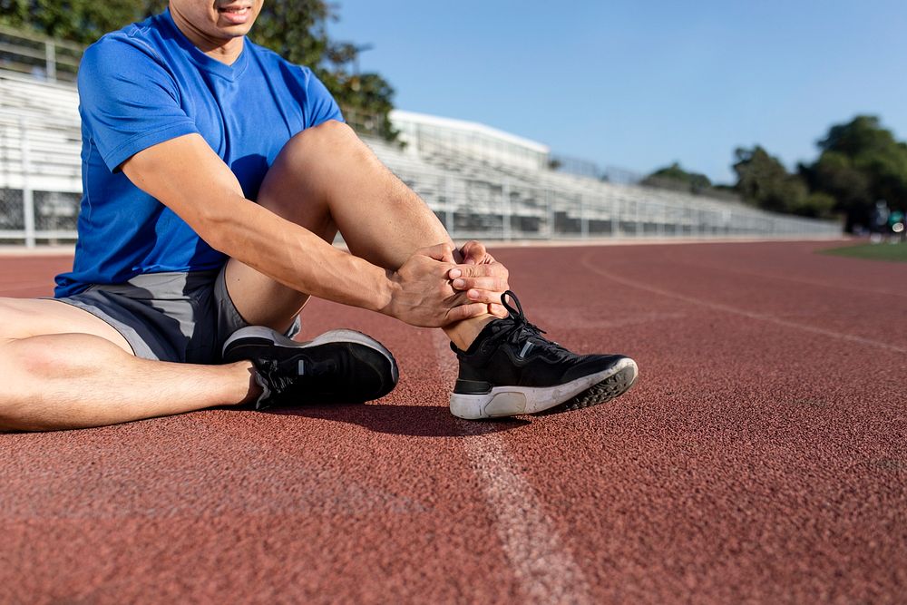Man getting hurting his ankle and sitting on the track 