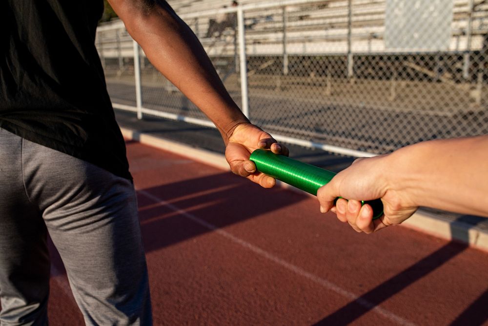 Team mate relaying the baton to another athlete 